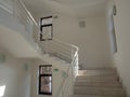 A stairwell with light steps with white railings and white walls and windows in dark frames Royalty Free Stock Photo