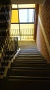 Stairwell in a modern residential apartment building with warm light coming from yellow stained glass window Royalty Free Stock Photo