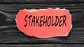 STAKEHOLDER - word on a red torn piece of paper on a dark wooden background
