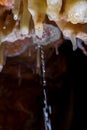 Stalactite formation with water stream in the cave