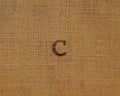 Stamp letters on linen fabric. Letter C.