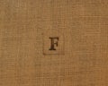 Stamp letters on linen fabric. Letter F.