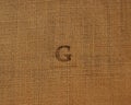 Stamp letters on linen fabric. Letter G.