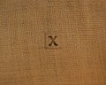 Stamp letters on linen fabric. Letter X.