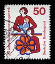 A stamp printed in Germany showing a mother and child as well as woman