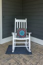 A stamped concrete front porch with a white rocking chair with a colorful pillow Royalty Free Stock Photo