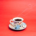 Stamped mug with steaming coffee. Soft smoke. Red background.