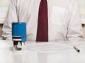 Stamping document in office, seal on foreground with businessman in tie sitting at desk on background