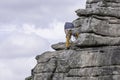 Rock climber standing on rocky ledge fixing assecuration point.