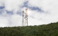 Stanchion of Telecommunication mast TV antennas wireless technology on a hilltop of green mountain, blue sky and cloud Royalty Free Stock Photo