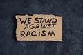 We stand against racism on cardboard banner over dark background