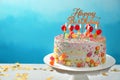 Stand with beautiful tasty birthday cake on table against color background Royalty Free Stock Photo