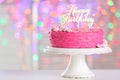 Stand with delicious birthday cake on table against blurred lights Royalty Free Stock Photo