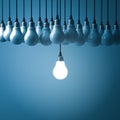 Stand out from the crowd and different creative idea concepts , One hanging light bulb glowing with unlit incandescent bulbs on da Royalty Free Stock Photo