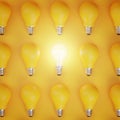 Stand Out Idea Concept. Glowing Bulb Between Unlit Yellow Bulbs Flat Lay Minimal Royalty Free Stock Photo