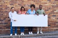 We stand together on this one. a group of young people holding a blank banner against an urban background outdoors. Royalty Free Stock Photo