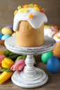 Stand with traditional Easter cake, tulips and colorful eggs on wooden table Royalty Free Stock Photo