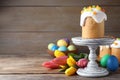 Stand with traditional Easter cake, tulips and colorful eggs on wooden table. Space for text Royalty Free Stock Photo