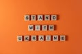 Stand with Ukraine word phrase in wooden letters. Motivation and slogan. Orange background