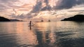 Beautiful blonde woman on stand up paddle board on holiday during sunset with yachts in the background in the Caribbean. Royalty Free Stock Photo