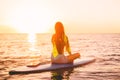 Stand up paddle boarding on a quiet sea with sunset colors. Woman meditation on sup board Royalty Free Stock Photo