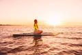 Stand up paddle boarding on a quiet sea with sunset colors. Woman on sup board