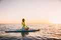 Stand up paddle boarding on a quiet sea with warm sunset colors. Young woman is relaxing on ocean Royalty Free Stock Photo