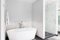 A standalone bathtub and marble lined shower.