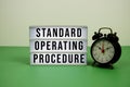 Standard Operating Procedure text on LED lightbox with alarm clock on green background Royalty Free Stock Photo