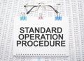 Standard Operation Procedure text written on paper with pen and glasses Royalty Free Stock Photo