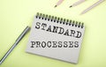 STANDARD PROCESSES text on the notebook with pen on yellow background