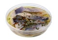 The standard round plastic container with marinated salty fillet of Norwegian herring fish with spices isolated macro