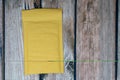 Standard yellow blank bubble mailer packaging isolated on a wooden background.