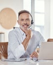 On standby to help find a solution. a mature man using a headset and laptop in a modern office. Royalty Free Stock Photo