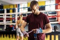 Standing adult man wrapping hands with clored boxing wrap for training in the gym