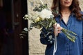 In blue clothes. Beautiful woman is with flowers in hands outdoors Royalty Free Stock Photo