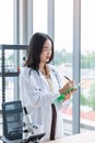 Standing asian nutritionist doctor woman writing on paper green board in laboratory room