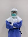 Standing Asian woman doctor wear full Personal Protective Equipment PPE and PAPR Powered Air Purifying respirator and surgical Royalty Free Stock Photo