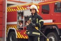 Standing with axe in hands against truck. Woman firefighter in uniform is at work in department Royalty Free Stock Photo
