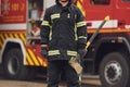 Standing with axe in hands against truck. Woman firefighter in uniform is at work in department Royalty Free Stock Photo