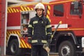 Standing with axe in hands against truck. Woman firefighter in uniform is at work in department Royalty Free Stock Photo