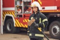 Standing with axe in hands against truck. Woman firefighter in uniform is at work in department Royalty Free Stock Photo