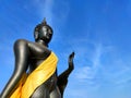 Standing Black Buddha statue Sukhothai style Wear yellow cloth and sky