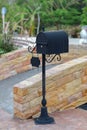 standing black metal mailbox on brick footpath Royalty Free Stock Photo