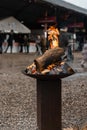 Standing bonfire spreading heat and cozyness at an outdoor market on a rainy day