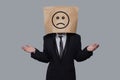 Standing business person paper bag head with sad emoticon on gray background