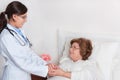 Standing Doctor comforts senior patient Royalty Free Stock Photo