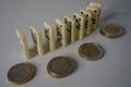 Standing domino bricks in curved pattern, Euro coins lying next to them Royalty Free Stock Photo