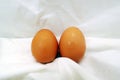 One Pair Of Fresh Eggs On The Wrinkled White Fabric Background