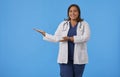 Female internist smiling presenting and pointing with palm of hand to copy space and looking at camera